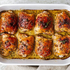 A casserole dish filled with baked honey mustard chicken thighs