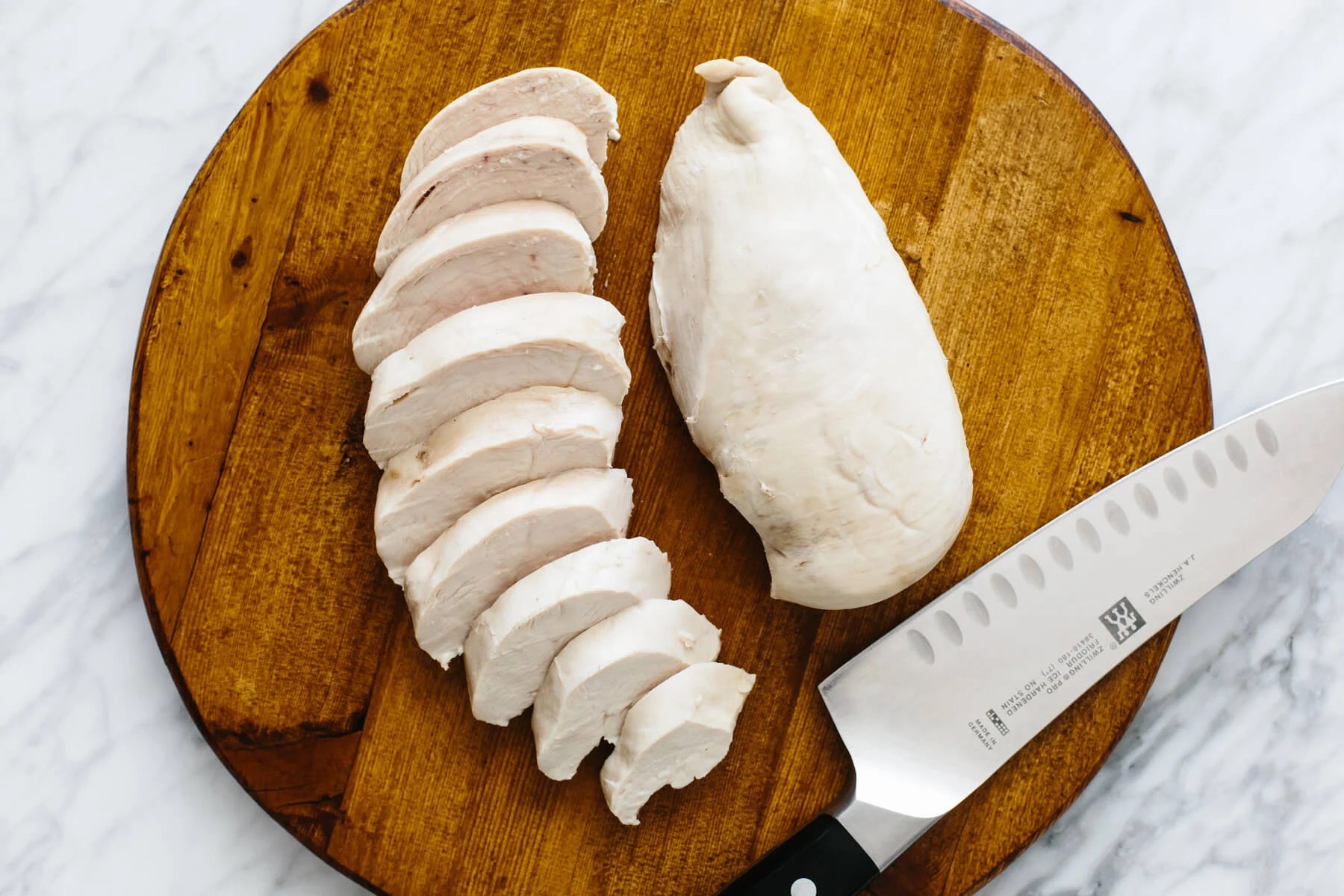 Slicing poached chicken for chicken salad recipe.