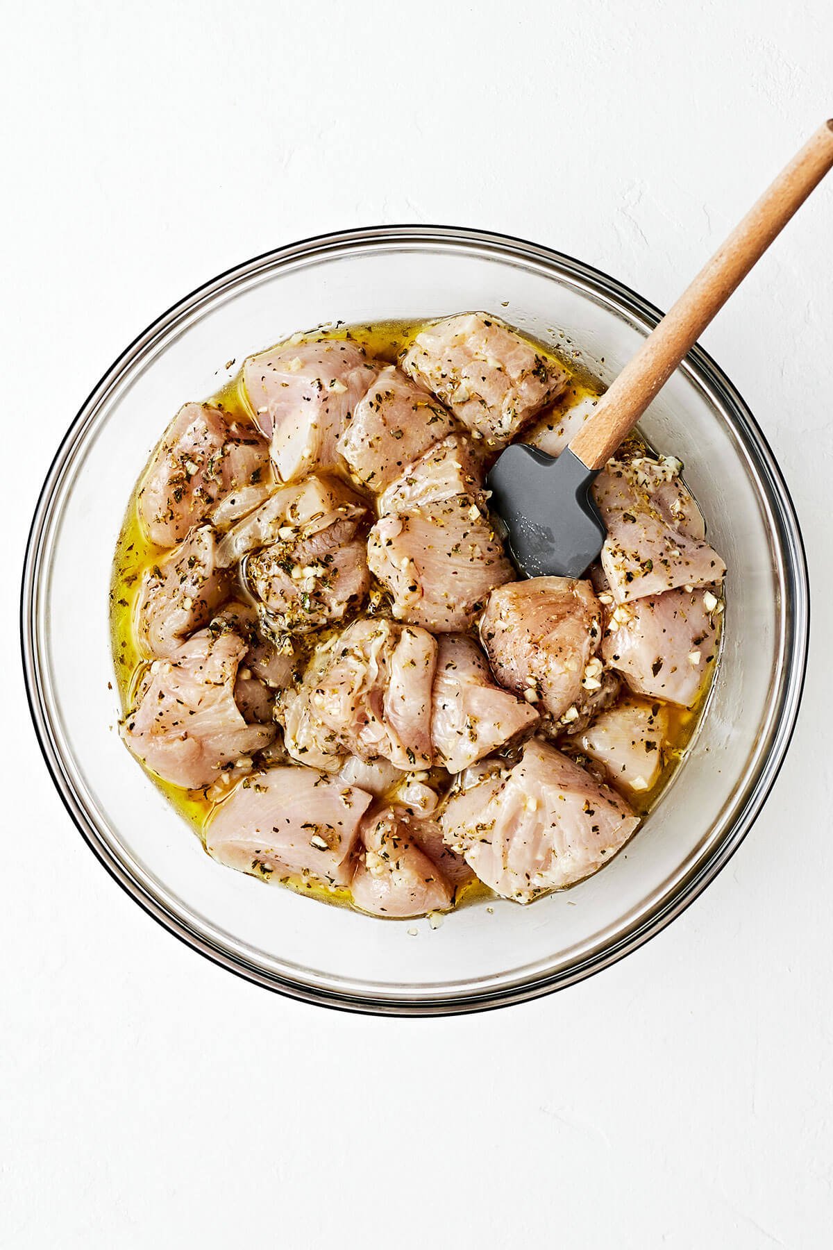Chicken souvlaki being marinated in a bowl