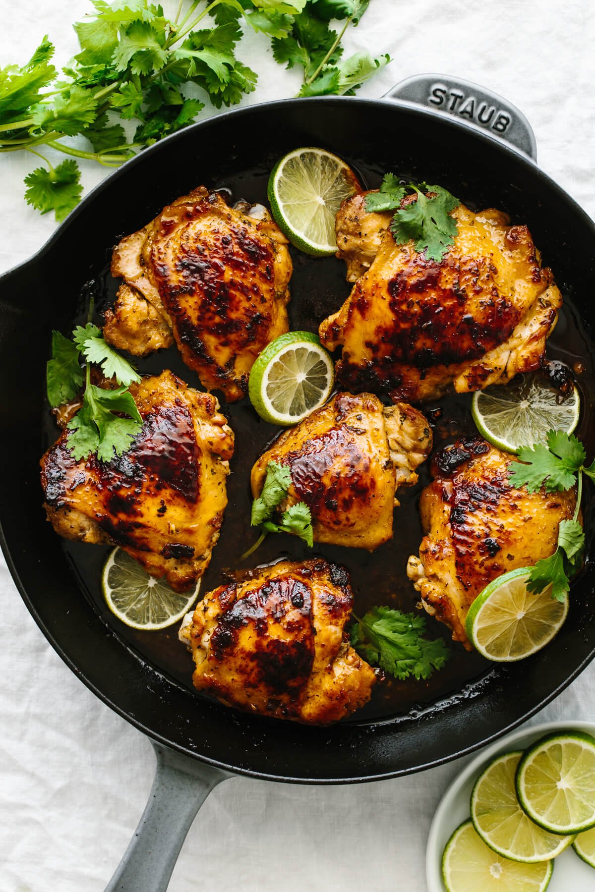Six cooked chicken thighs with cilantro lime flavors in a fry pan.