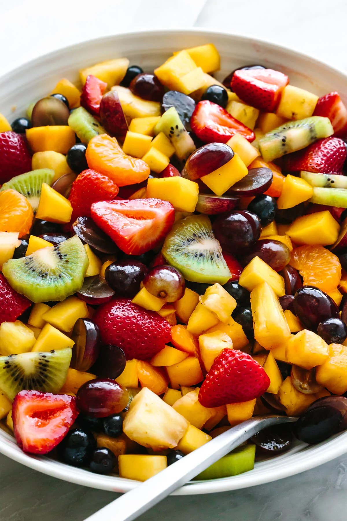 A large bowl of fruit salad with a spoon.