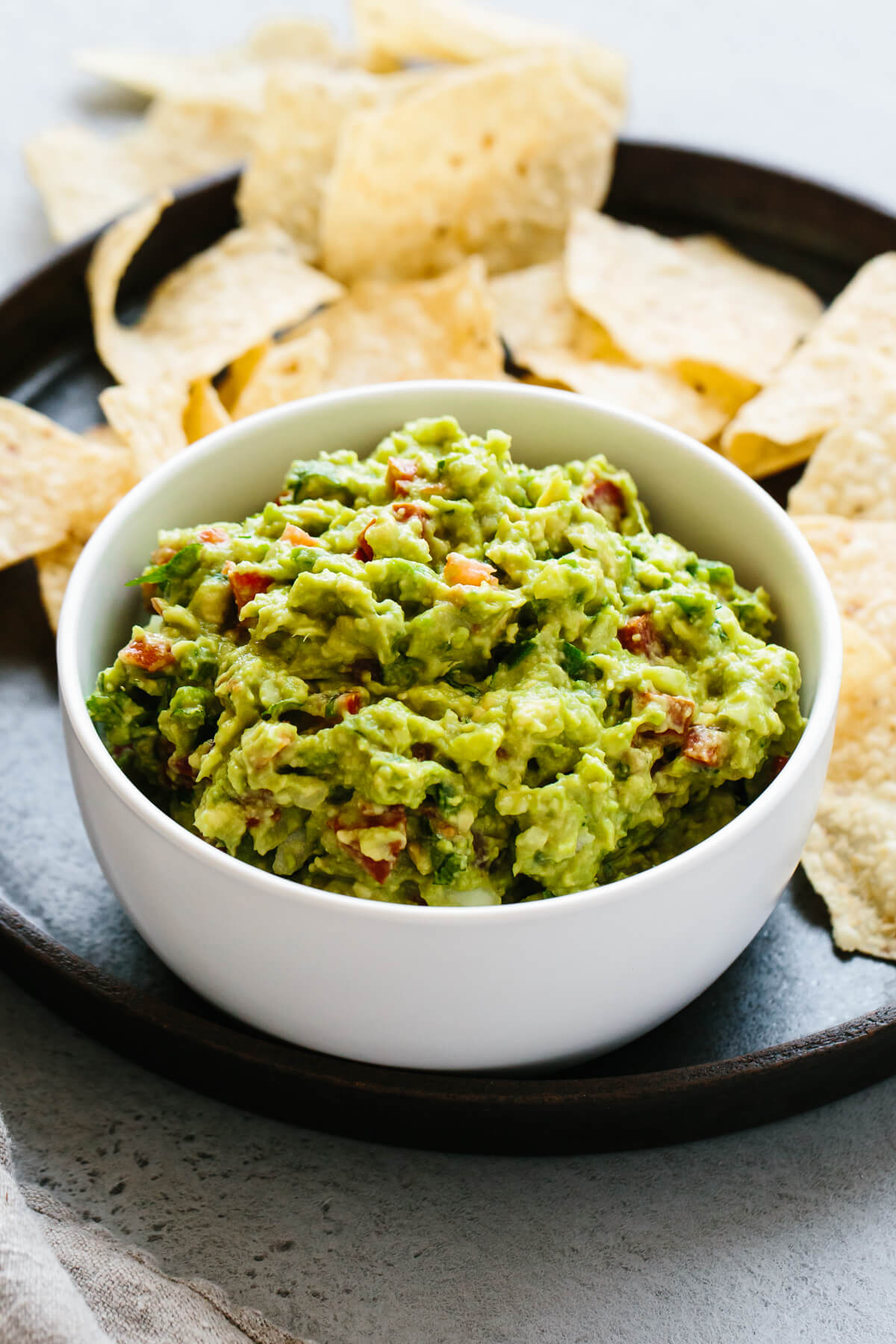 A bowl of fresh, authentic guacamole next to tortilla chips.