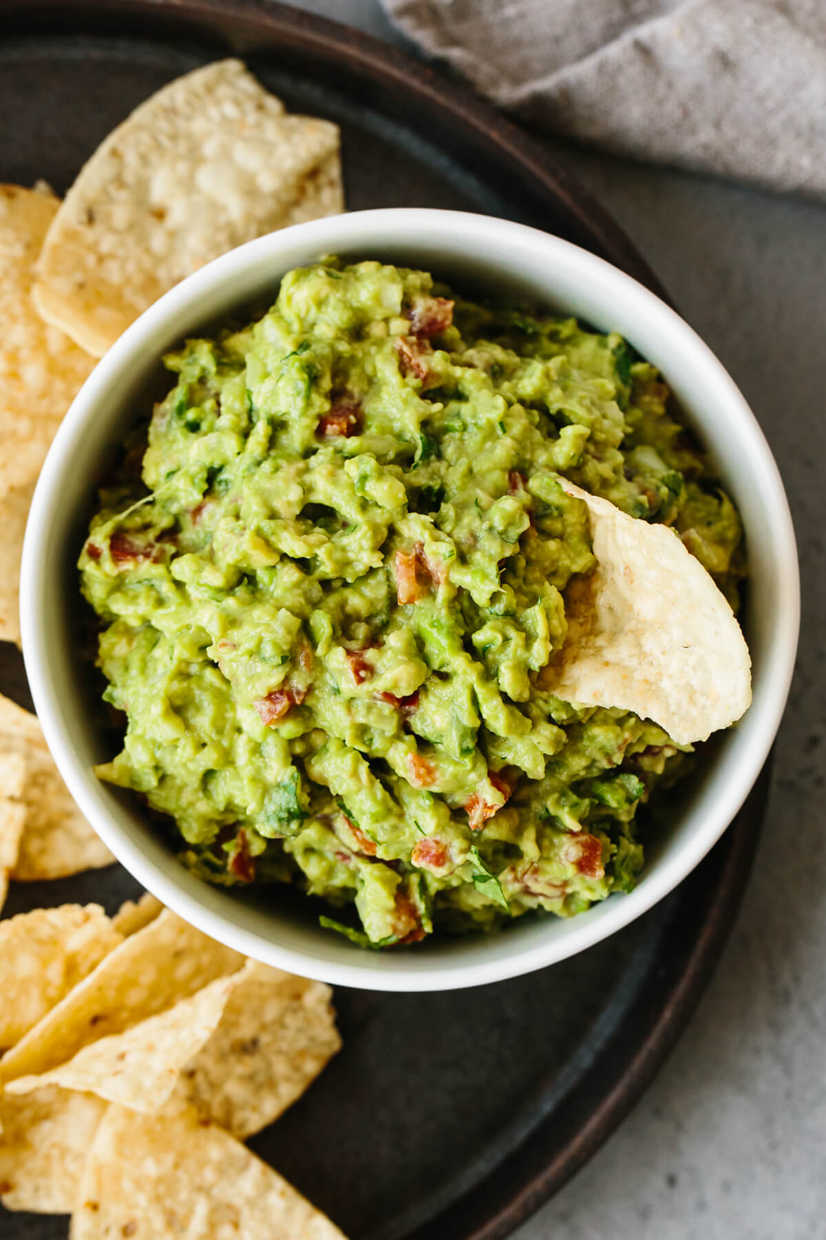 Guacamole in a bowl with a chip dipping in.