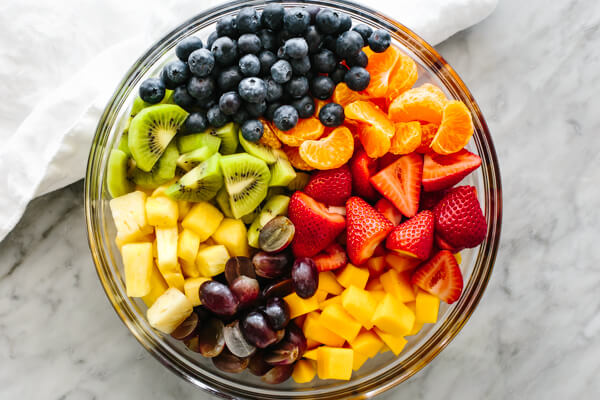 Adding fruits in a large bowl for a fruit salad
