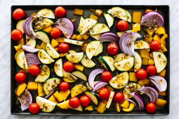 A sheet pan with roasted vegetables before adding Greek chicken.