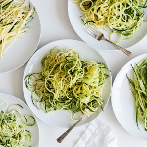Five plates of zucchini noodles made different ways.