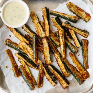 These baked zucchini fries are ultra cheesy and flavorful with freshly grated Parmesan cheese. They're also gluten-free, low-carb, paleo and keto-friendly for a delicious, healthy snack recipe.