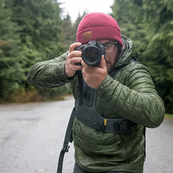 Man wearing a camera harness and shooting a photo while birding